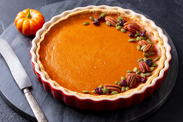 Wall Mural - Pumpkin pie, tart in baking dish. Black background. Close up.