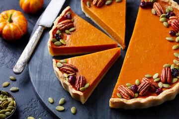 Canvas Print - Pumpkin pie, tart with pecan nuts on black marble cutting board. Close up.