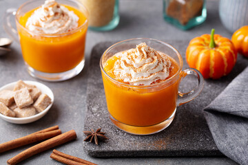 Wall Mural - Pumpkin spice latte with whipped cream in glass cups. Grey background. Close up.