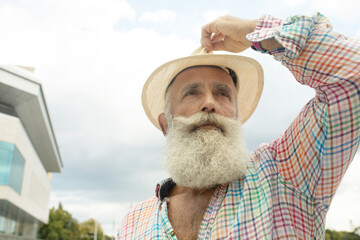 Portrait of stylish handsome adult man with beard standing outdoors.