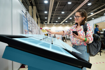 Wall Mural - A woman with phone using contactless self service kiosk