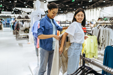 Canvas Print - Two girls trying on coats in clothing store