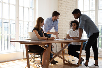 Sticker - Concentrated diverse multiracial businesspeople sit at desk in office discuss paperwork at briefing together, focused multicultural colleagues brainstorm cooperate at meeting, collaboration concept