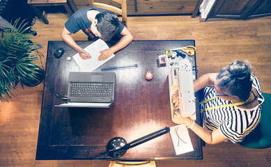 Mother and son working at home because of the pandemic. Covid 19. Mother sewing masks, son doing homework at home. Work at home concept