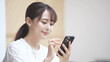 © aijiro - スマートフォンを操作している若い女性