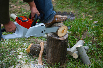 A man with an electric saw cuts a log. Woodsman at the work. Technique at work.