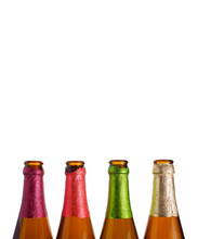 4 Bottle Necks Are In A Row, Colored Foil On The Necks White Background, Isolated