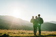 © Serhii - The daughter hug parents on nature. Mom, dad, and child walk in the grass. Family spending time together in mountain outside, on vacation. Family holiday trip concept. World Tourism Day. Back view.