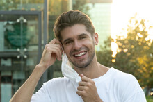 Portrait Of A Handsome Man With A Wide Smile Removing His Face Mask 