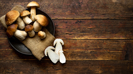 Fresh forest mushrooms /Boletus edulis (king bolete) / penny bun / cep / porcini in an old bowl / plate on the wooden dark brown table, top view background