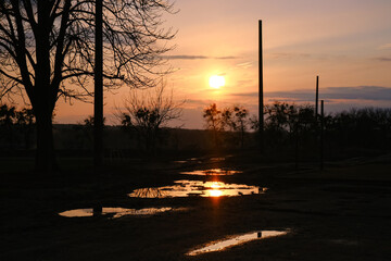 Sunset clouds after the rain over field with puddles