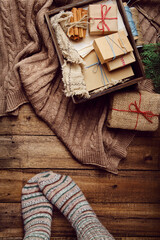 Wall Mural - Christmas, New Year composition with gift boxes, knitted blanket and women feet on wooden floor. Preparing for the winter holidays