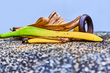 Wall Mural - View to a banana peel lying on a concrete bollard with pebbles next to a metal ring.