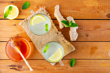 Wall Mural - Ginger tea with lemon and honey. Two cups of ginger tea with mint on wooden background. Top view