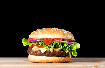 Delicious cheeseburger with beef cutlet, lettuce, tomato slices, red onion and sesame seed bun.