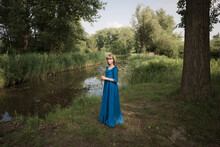 Portrait Of Teenage Girl In Blue Dress Holding Flowers While Standing By River