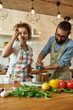 © Svitlana - Italian man adding pepper, spice to the soup while woman tasting it. Couple preparing a meal together in the kitchen. Cooking at home, Italian cuisine