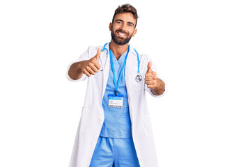 Young hispanic man wearing doctor uniform and stethoscope approving doing positive gesture with hand, thumbs up smiling and happy for success. winner gesture.