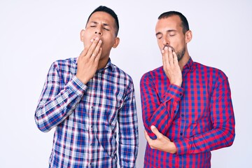 Young gay couple of two men wearing casual clothes bored yawning tired covering mouth with hand. restless and sleepiness.