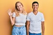 © Krakenimages.com - Young interracial couple wearing casual white tshirt showing and pointing up with fingers number five while smiling confident and happy.