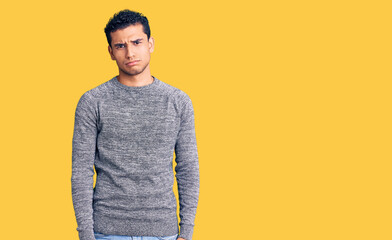 Hispanic handsome young man wearing casual sweater depressed and worry for distress, crying angry and afraid. sad expression.