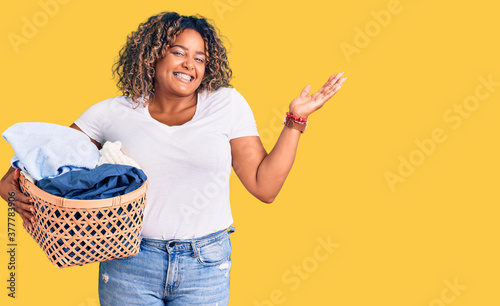 Fotografía Young african american plus size woman holding laundry basket celebrating victor