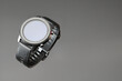 © Mikhail Rychkov - Wireless smart watch in a round matte black case with risks on the rim and a silicone strap on a gray background with space for text.