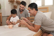 © sirichai - Young married LGBT parent couples play with adopted child in bedroom