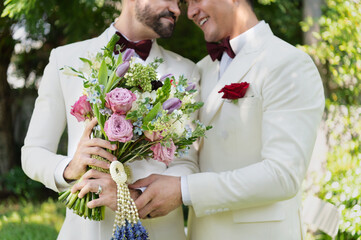 Young married LGBT couples celebrate a romantic wedding ceremony together with a bouquet flower in a suit