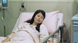 view form medical partition taiwanese female in vegetative state resting alone on bed in bright hospital.