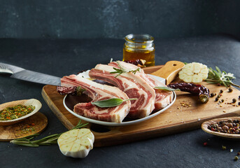 Canvas Print - Raw lamb ribs with ingredients for cooking: salt, pepper, olive oil and herbs on a plate with a wooden handle