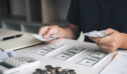 Wall Mural - Asian men are holding banknotes in cash and placed on the table with the idea of saving money.