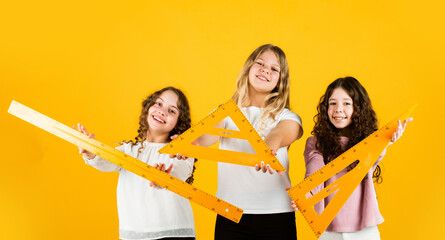 Clever kids. Group studying. Teamwork and help. Developing cognitive skills. Study together. Education concept. School friendship. School students learning geometry. Girls with triangle ruler