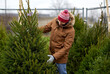 © Syda Productions - winter holidays, sale and people concept - happy smiling man choosing or selling christmas tree at street market