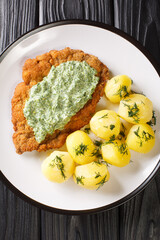 Canvas Print - German schnitzel with boiled potatoes and Frankfurt green sauce close-up in a plate on the table. Vertical top view from above