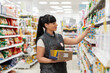 © _KUBE_ - A portrait of young Caucasian woman, an employee of a supermarket, is engaged in putting goods on display. Side view. Concept of business, shopping and work