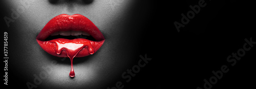 Red Paint dripping, lipgloss drops on sexy lips, bright liquid paint on beautiful model girl\'s mouth, black skin. Lipstick. Make-up. Beauty face makeup, close up. Isolated on black background