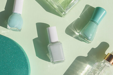 flat lay of mint color nail polishes, beauty serum, parfume and gift box on a green background