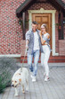 © Тарас Нагирняк - Young couple in front of the big house with beautiful labrador. A man hugging a woman and holding a dog on the leash