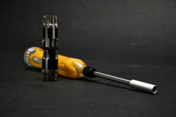 Screwdriver with a universal set of bits, on a dark background.