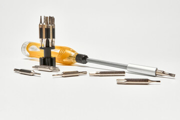 Screwdriver with a universal set of bits, on a light background.