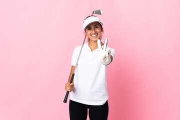 Young hispanic woman over isolated pink background playing golf and and showing victory sign