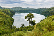 A small lake with reflected clouds on its still surface surrounded with rich vegetation and farm fields in the background near the Bwindi National Park during a cloudy day in uganda