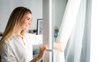 © leszekglasner - Beautiful smiling woman opening window at the morning