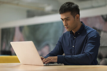 Young asian businessman working with laptop in office.