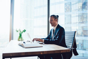 Wall Mural - Determined businessman typing on laptop in contemporary workplace