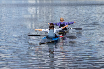 Young girl and boy train to keep balance on a kayak, canoe. Water sports. The training process.