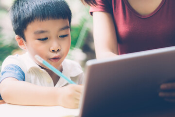 Wall Mural - Son using digital tablet computer for study and learn to internet online with mother together, education from home, family recreation, mom teach boy and homework with technology, lifestyle concept.