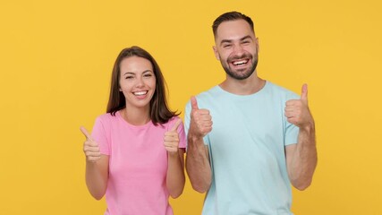 Wall Mural - Young fun couple friends woman man 20s in basic t-shirts posing isolated on yellow background studio. People emotions lifestyle concept. Look camera smiling doing phone gesture like says call me back