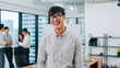 © tirachard - Portrait of successful handsome executive businessman smart casual wear looking at camera and smiling, happy in modern office workplace. Young Asia guy standing relax in contemporary meeting room.